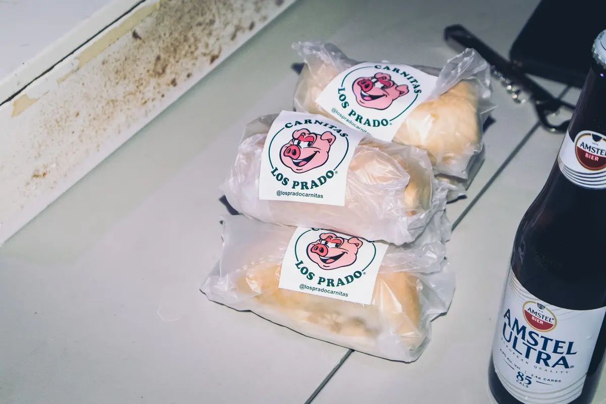 tortas de carnitas los prado y una cerveza sobre la mesa