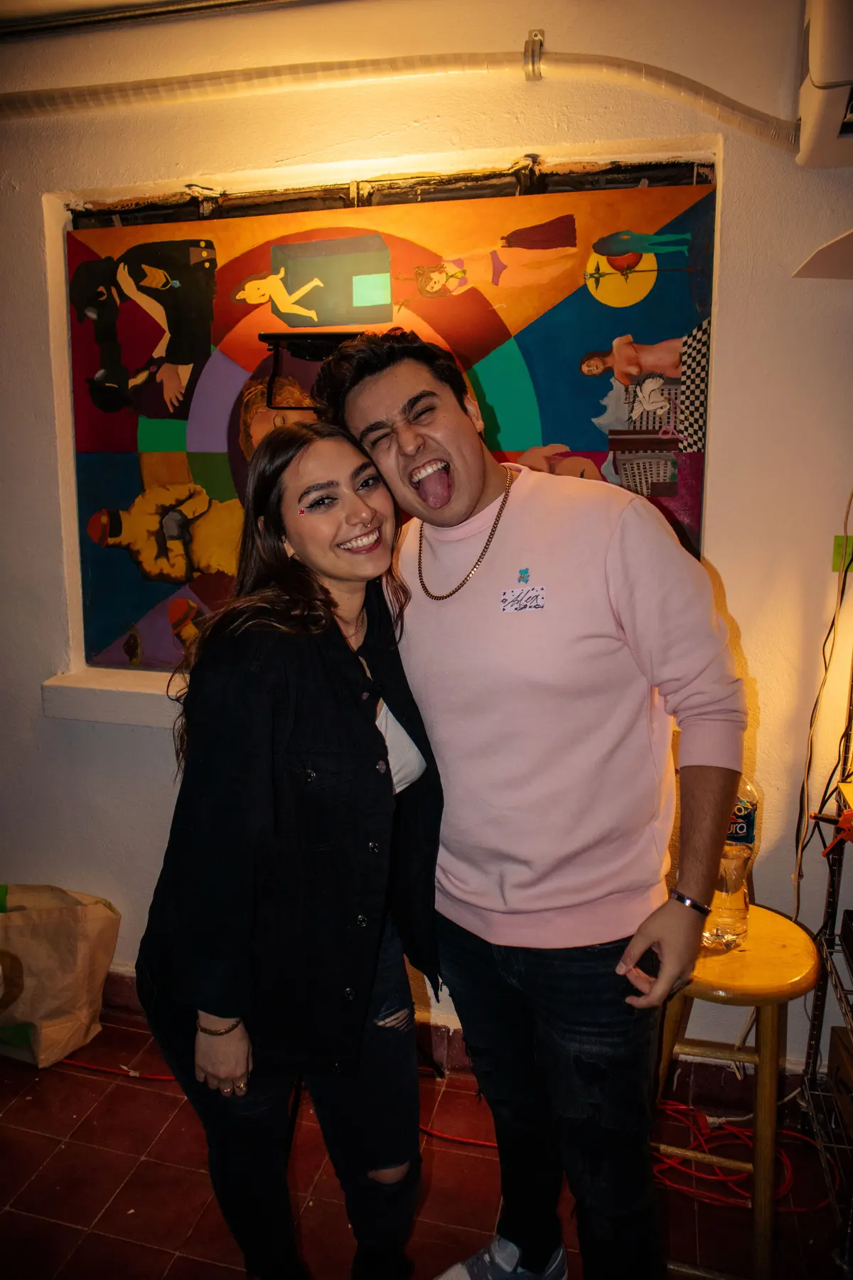 dos invitados abrazados frente a un cuadro de colores