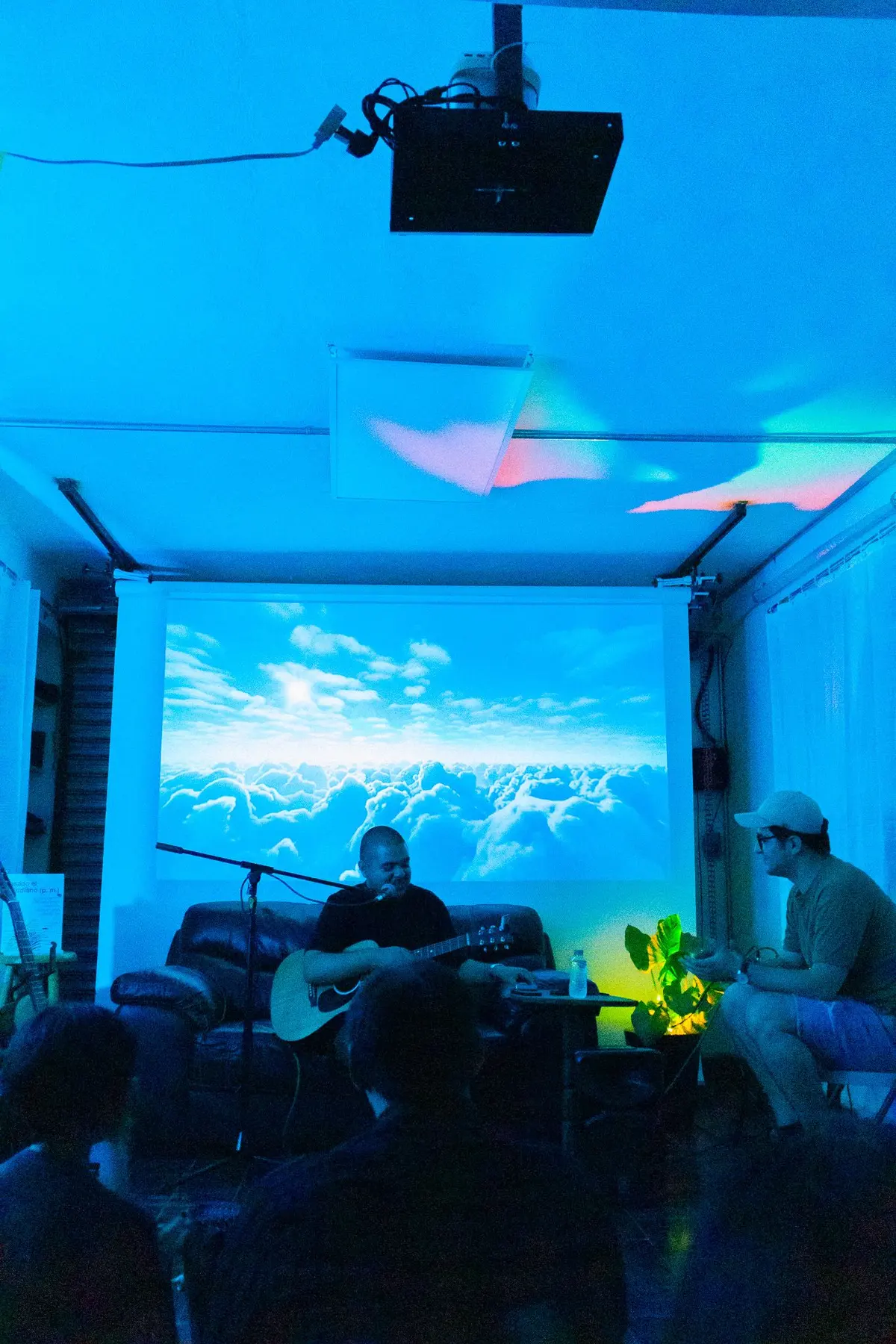 la sala azul con nubes proyectadas y un guitarrista sentado