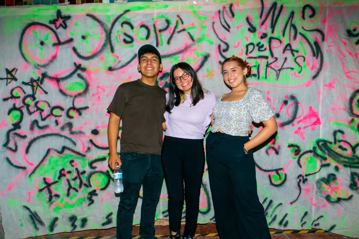 tres invitados frente a la manta pintada con aerosol