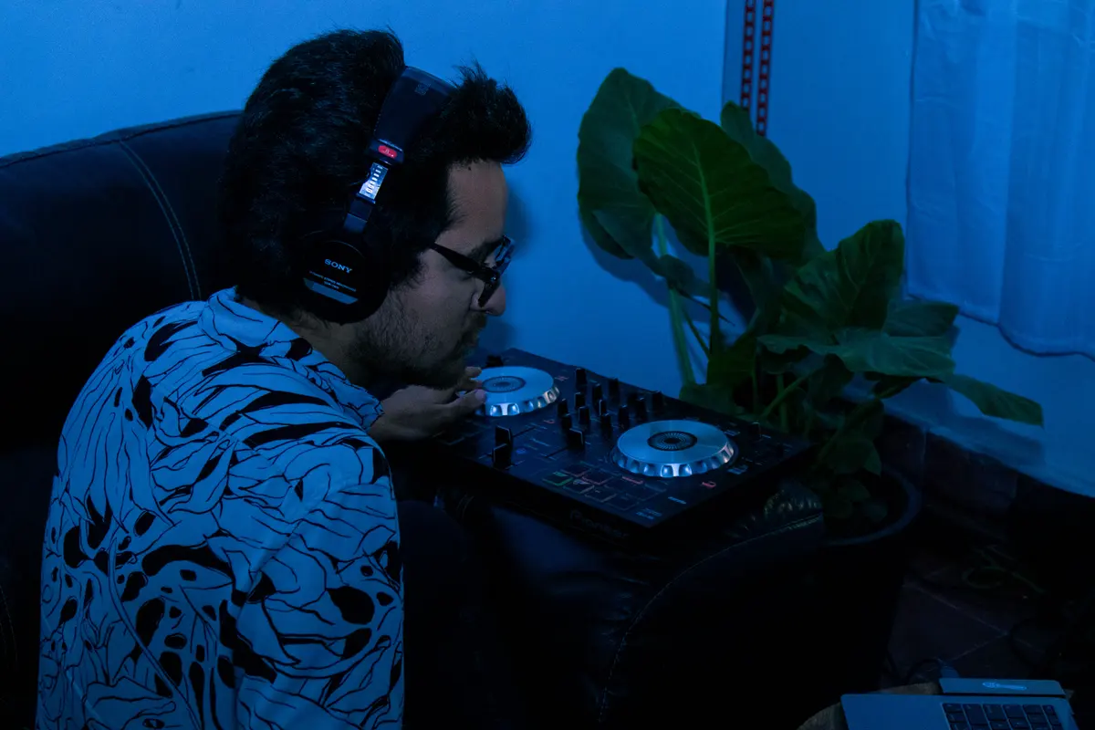 el dj con audífonos frente al controlador, en luz azul