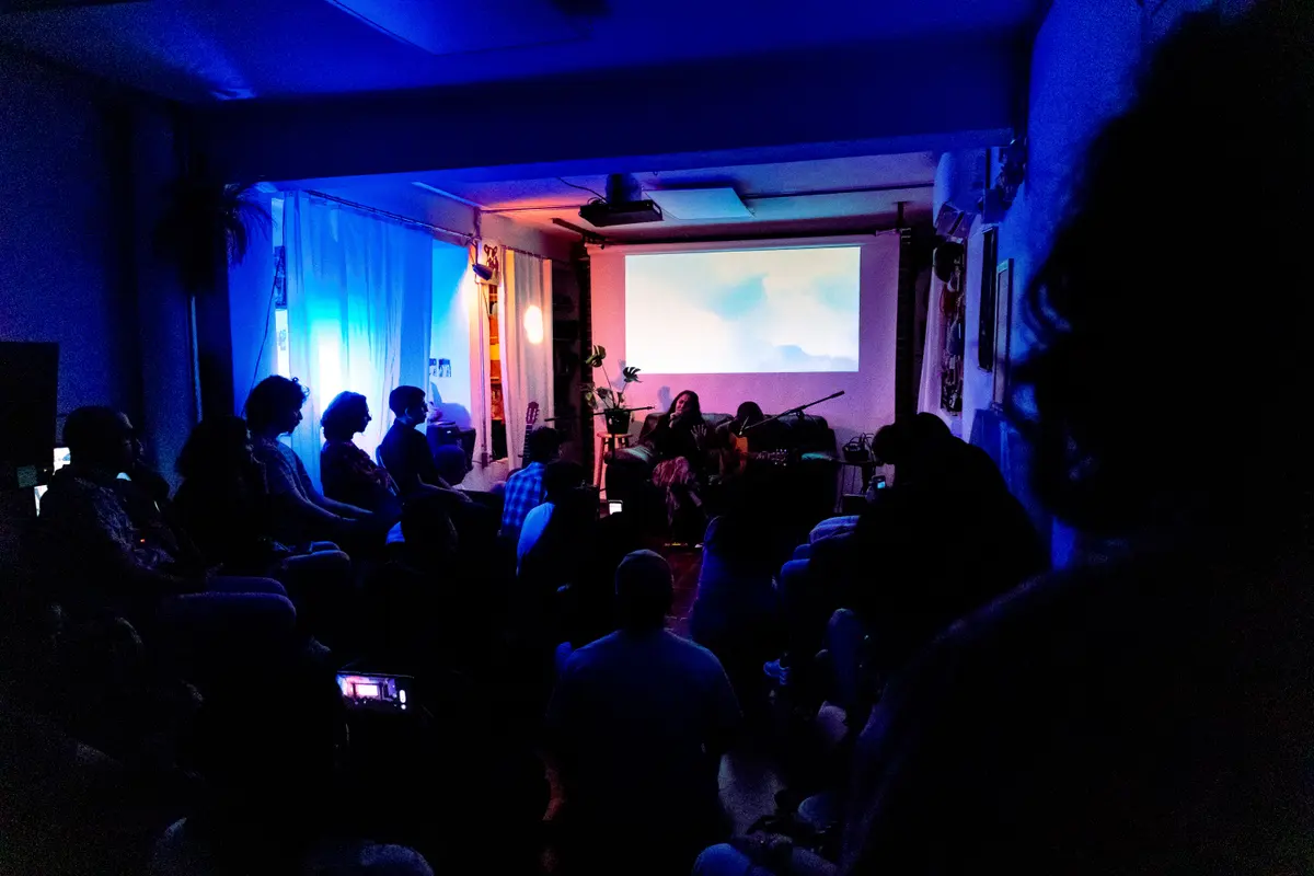 la sala a oscuras, en azul, con el público frente a la proyección